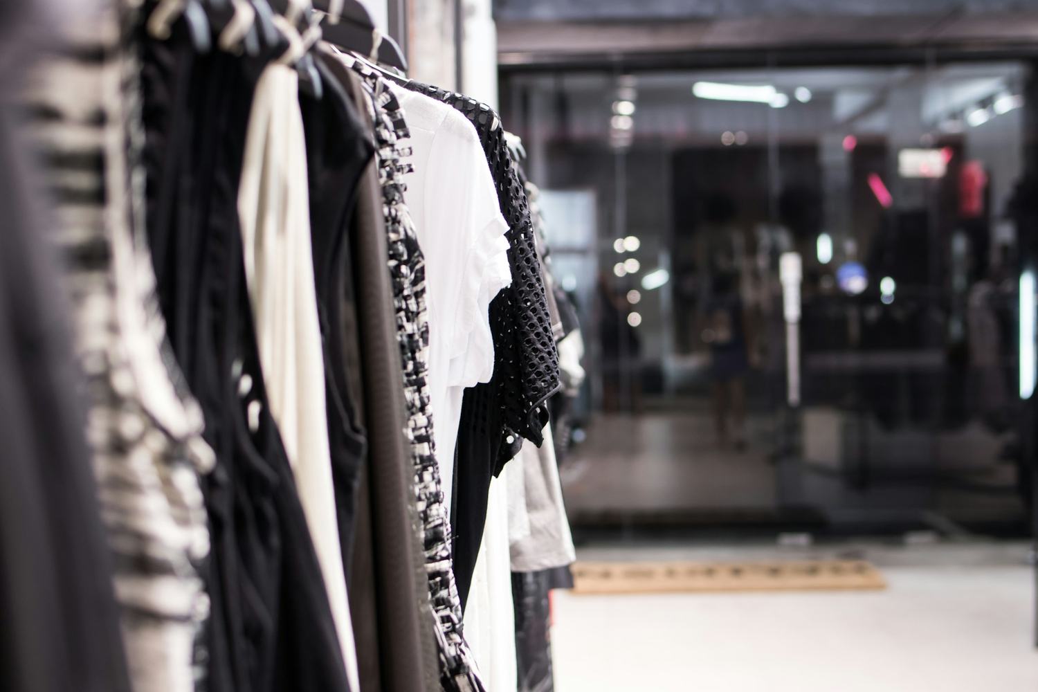 Rows of hanging garments in a dark, quiet showroom.