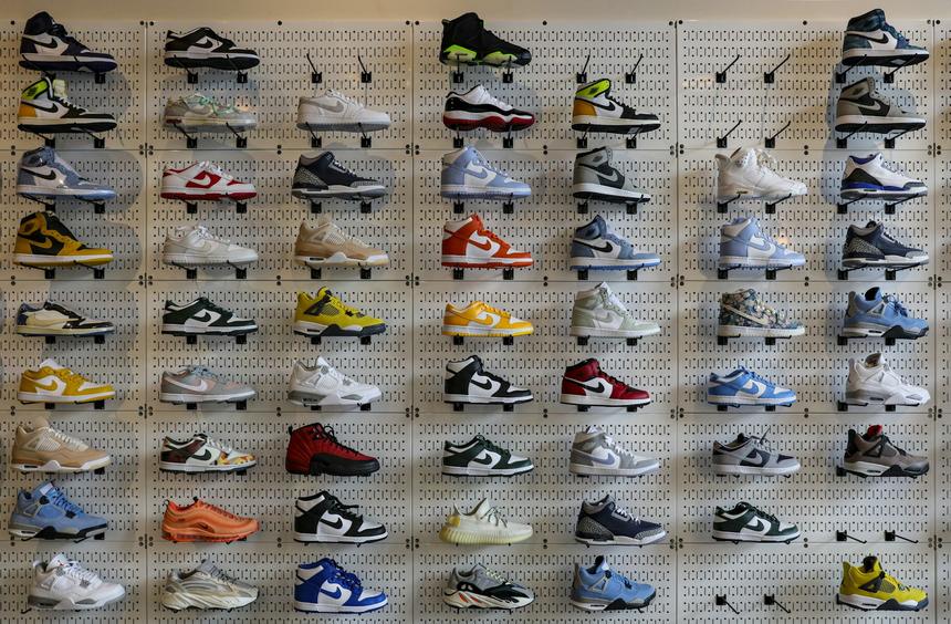 A wall of sneakers on shelves in a dark retail space.